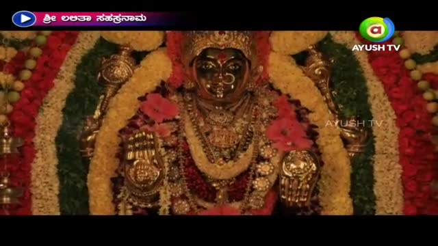 A golden idol, draped in garlands of flowers, is the focus of the broadcast on Ayush TV. The deity's dark face is framed by a jeweled crown and ornate necklaces.
