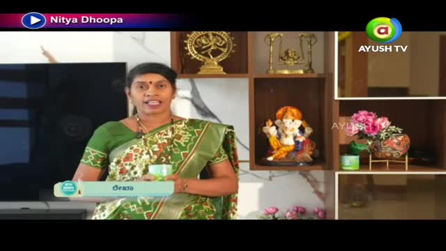 A woman in a green sari speaks directly to the camera, holding a small cup. Behind her, a shelf displays religious statues and Ayush TV's logo.
A woman in a green sari speaks directly to the camera, holding a small cup. Behind her, a shelf displays religious statues and Ayush TV's logo.
