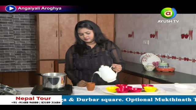 A woman in a black top pours from a white teapot into a small brown cup. The scene unfolds in a kitchen setting, likely as part of a segment on Ayush TV.
