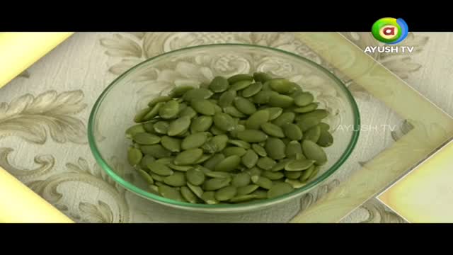 A clear glass bowl overflows with bright green pumpkin seeds. The seeds are piled high, their smooth surfaces catching the light.