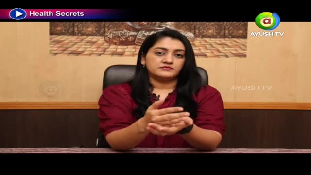 A woman in a maroon top speaks, her hands clasped in front of her. The Ayush TV logo appears on screen.