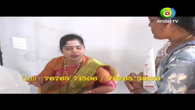 A woman in an orange and green sari gestures as she speaks. Another woman holds a white bottle, looking towards her. A phone number flashes on the screen, indicating a call to action.