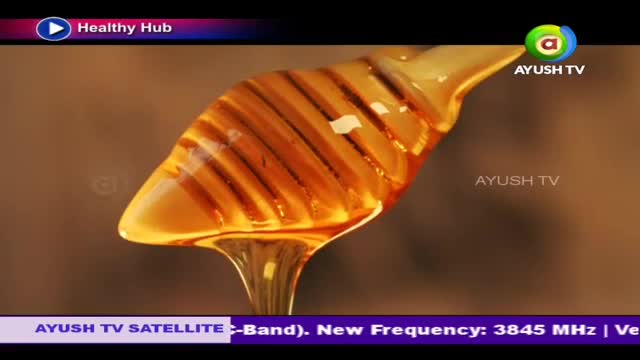 Golden honey drips slowly from a wooden dipper. The viscous liquid catches the light as it falls.