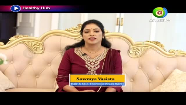 A woman in a maroon outfit speaks from a plush sofa, her name and profession displayed below. The Ayush TV logo appears in the corner, indicating a broadcast from India. A woman in a maroon outfit speaks from a plush sofa, her name and profession displayed below. The Ayush TV logo appears in the corner, indicating a broadcast from India.