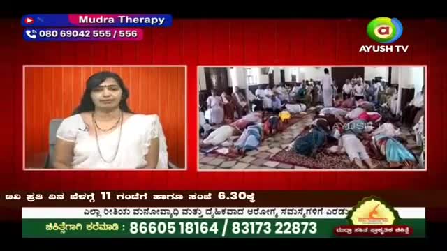 A woman in a white sari speaks from a studio, while a split screen shows a large group of people in a hall, many of them lying on the floor in prayer. The Ayush TV logo is visible in the corner.