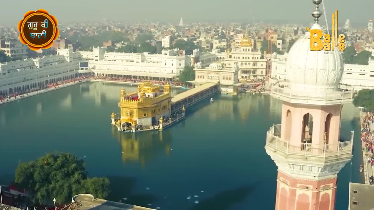 The Golden Temple shimmers, reflecting in the still water, as people walk along the causeway. From the tower, the Balle Balle logo sits above the bustling scene.
