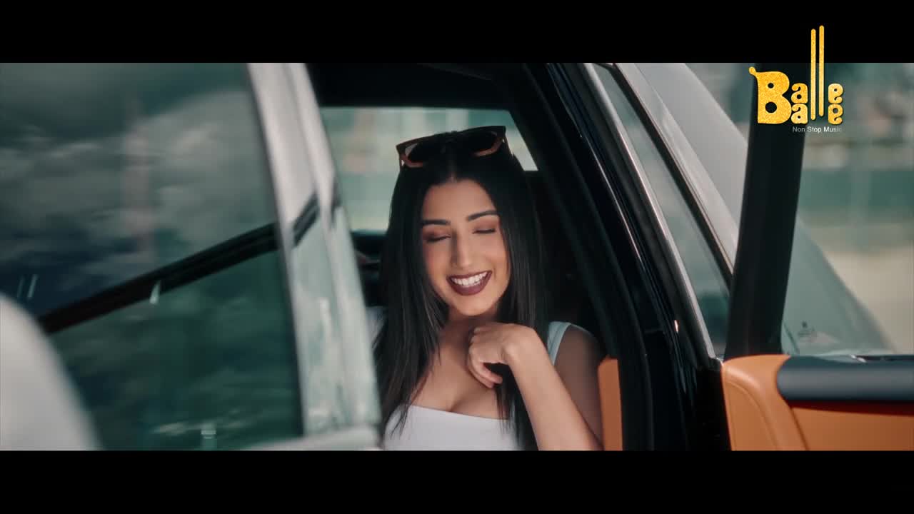 A woman with long, dark hair smiles broadly from inside a car. The logo for Balle Balle music is visible in the corner.
