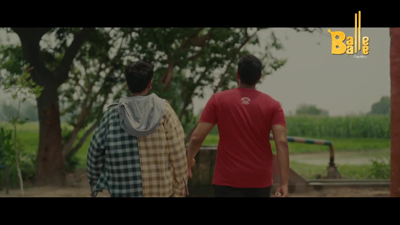 Two men walk away from me, holding hands. The one on the left wears a half-plaid shirt and a hoodie; the other, a red t-shirt, and the logo of Balle Balle is in the corner.
