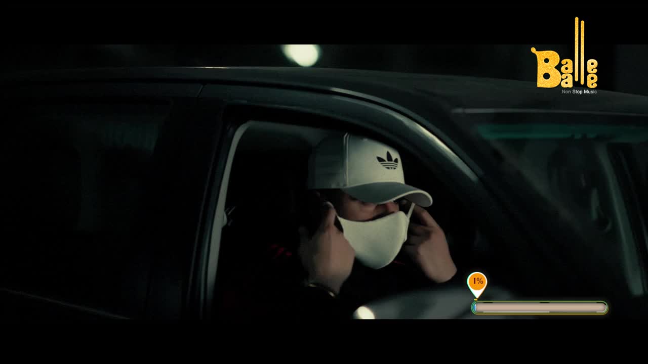 A man in a white cap and mask sits in a car, adjusting the mask with both hands. The Balle Balle logo is in the corner, and a progress bar indicates the video is just beginning.
