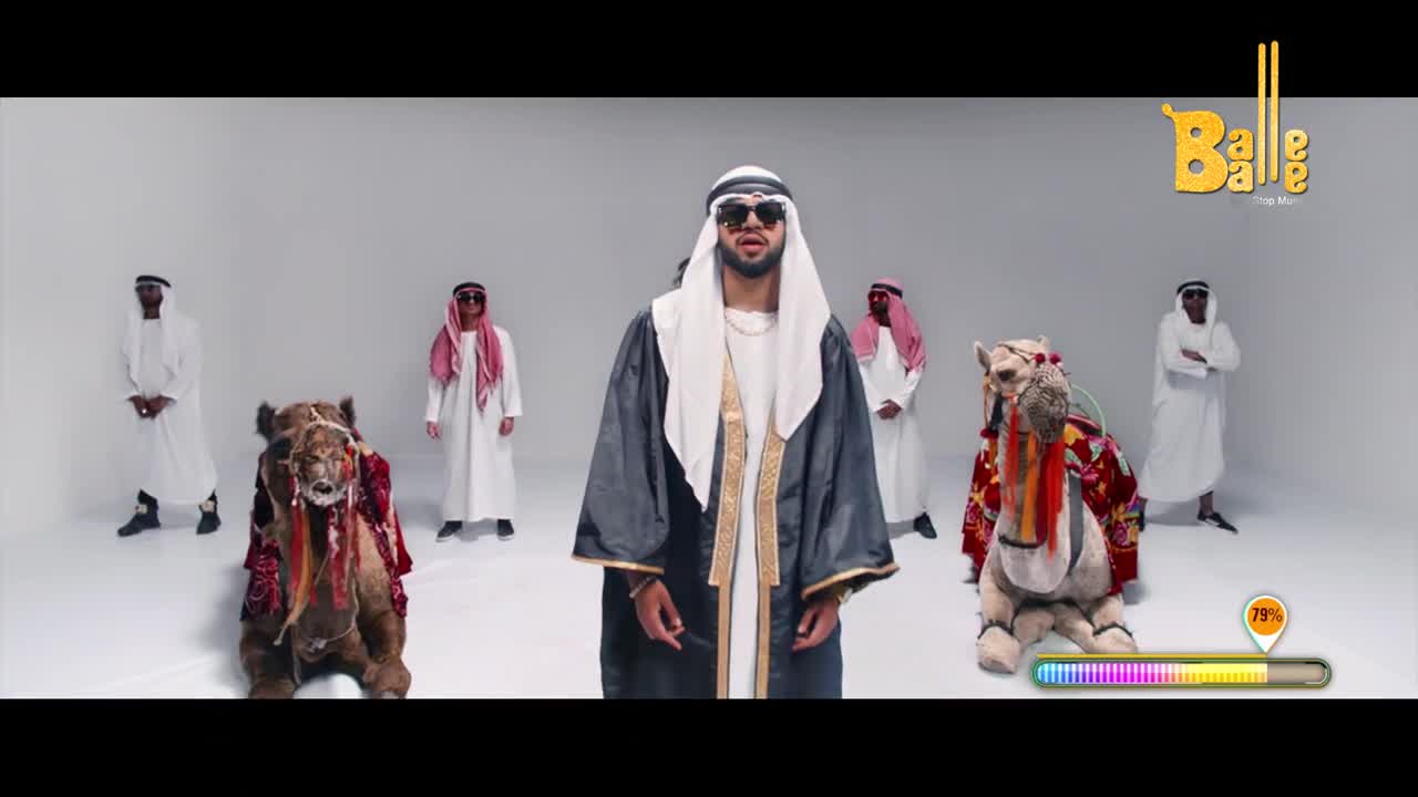 A man in a dark robe and sunglasses stands center stage, flanked by others in white robes and camels decked out in colorful fabrics. The "Balle Balle" logo sits in the corner, and a progress bar hovers near the bottom.
