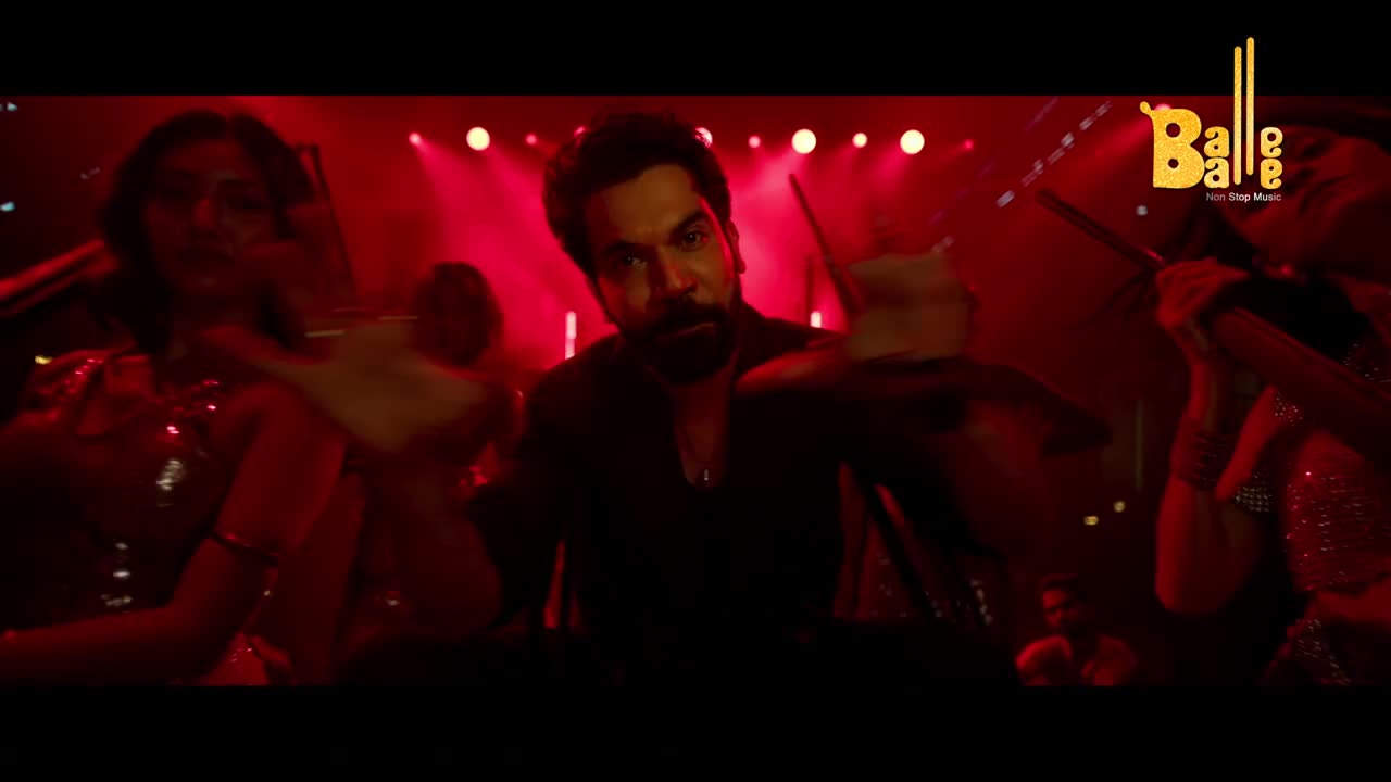 A man in a dark shirt holds up a drink, surrounded by dancers in a club bathed in red light. The "Balle Balle" logo sits in the corner, hinting at the music's energy.
