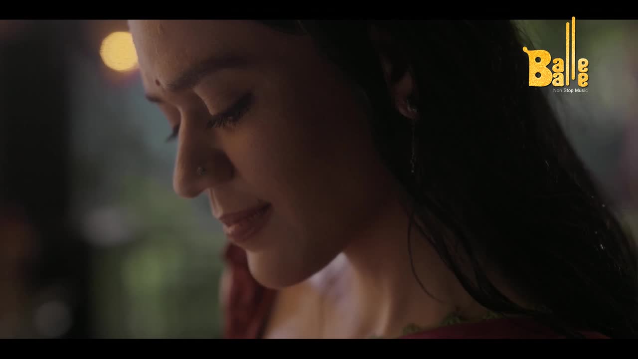 A woman, her gaze lowered, is illuminated by a soft light. The Balle Balle logo sits in the corner, hinting at the music video's setting.
