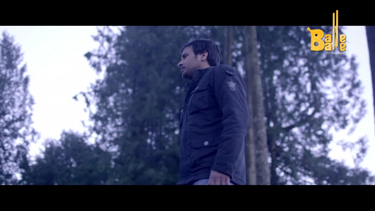 A man in a dark jacket stands in a forest, looking off to the side. The Balle Balle logo is visible in the upper right corner, hinting at a film or show.
