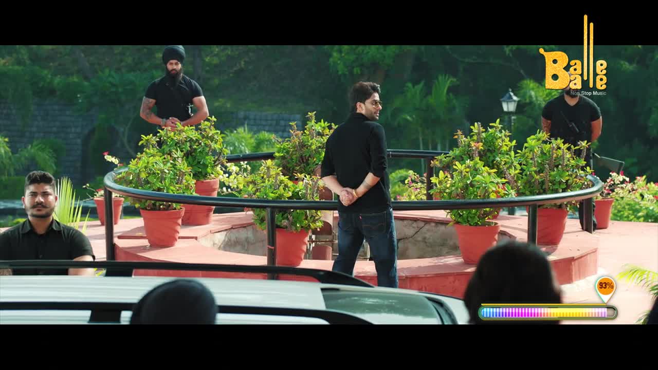 A man in a black shirt and jeans stands with his hands clasped behind his back, flanked by men in black, all seemingly guarding him. The scene appears to be part of a Balle Balle music video, with a progress bar displayed at the bottom.
