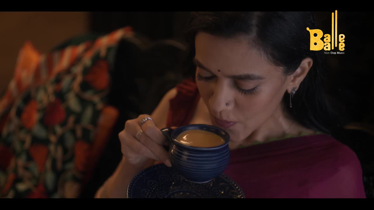 A woman in a maroon sari gently sips from a blue mug of tea. The "Balle Balle" logo sits in the corner, and the scene feels warm and intimate.
