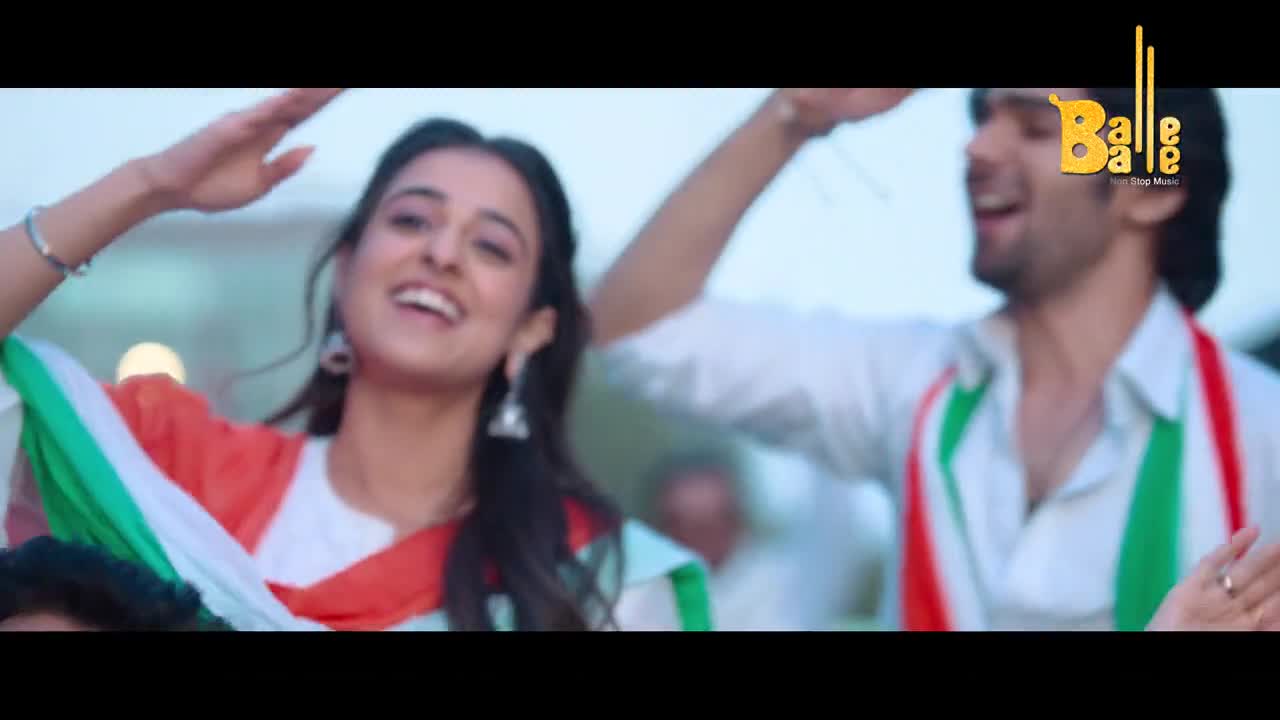 The woman is smiling, her arm raised, draped in a shawl of the Indian flag's colors. Beside her, a man with a scarf of the same colors joins in the joyful movement.
