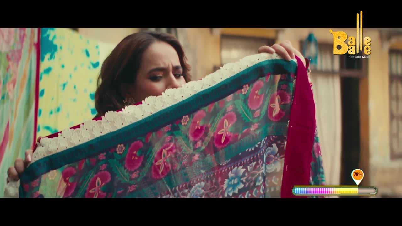 A woman is holding up a colorful dupatta, examining the intricate floral pattern. The scene feels like a moment from a Bollywood-inspired music video, with the "Balle Balle" logo in the corner.
