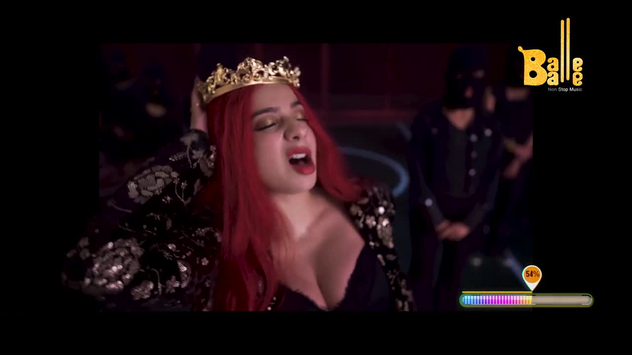 A woman with red hair and a crown is singing, her mouth wide open. Behind her, a shadowy figure in black stands still.
