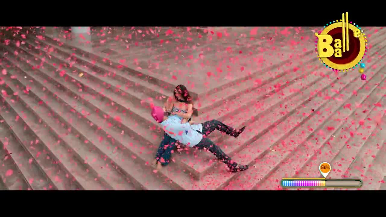 A man in a turban carries a woman down a flight of stairs, both surrounded by falling pink petals. The scene feels like a Bollywood dance sequence, with a "Balle Balle" graphic in the corner.
