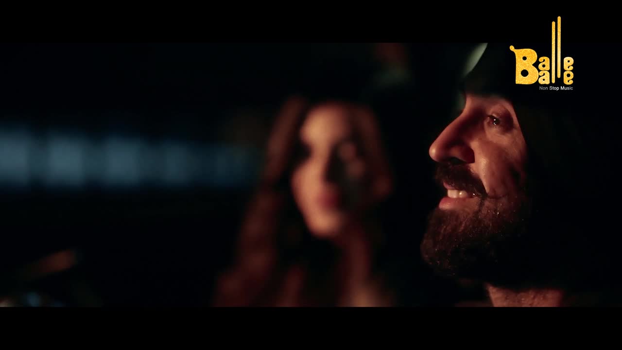 The man with the beard is smiling, his eyes lit up in the dim light. Behind him, a woman is out of focus, her face barely visible in the shadows.
The man with the beard is smiling, his eyes lit up in the dim light. Behind him, a woman is out of focus, her face barely visible in the shadows.