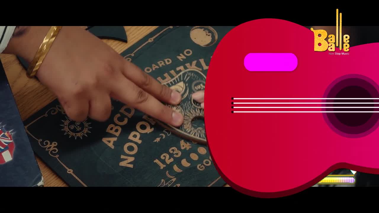 A hand, adorned with a gold bangle, rests on the planchette of a Ouija board. A vibrant red guitar graphic, likely from a Balle Balle music video, fills the right side of the frame.
