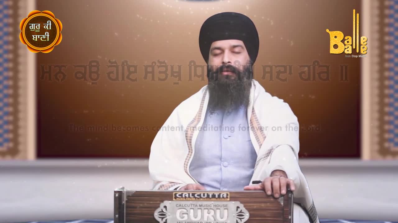 A man with a long beard sits with his eyes closed, hands resting on a harmonium. The backdrop features text in Punjabi, and the "Balle Balle" logo is visible in the corner.
