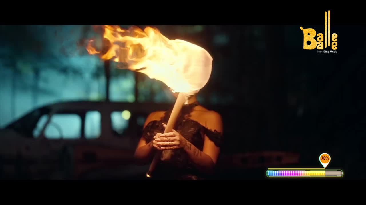 A woman, silhouetted against the night, holds a flaming torch aloft. The fire's light illuminates her face and the dark, lacy details of her dress.
