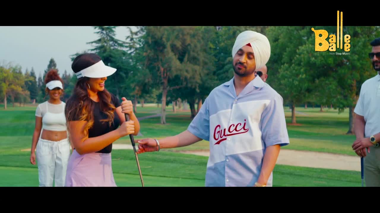 A woman in a black shirt and pink skirt grips a golf club, laughing. A man in a light blue shirt with "Gucci" across it stands beside her, looking towards her.