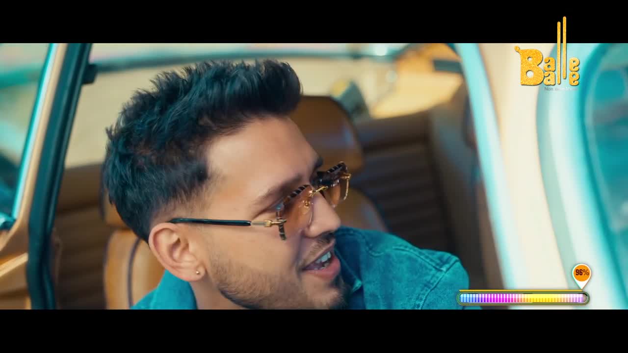 The young man in the driver's seat grins, his trendy glasses catching the light. A Balle Balle logo hangs in the corner, hinting at Punjabi music.