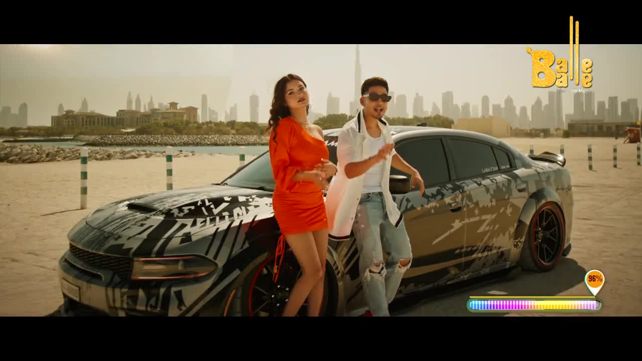 A young man and woman pose by a custom car on a sandy beach, with a city skyline in the distance. The "Balle Balle" logo suggests a vibrant Indian music video.