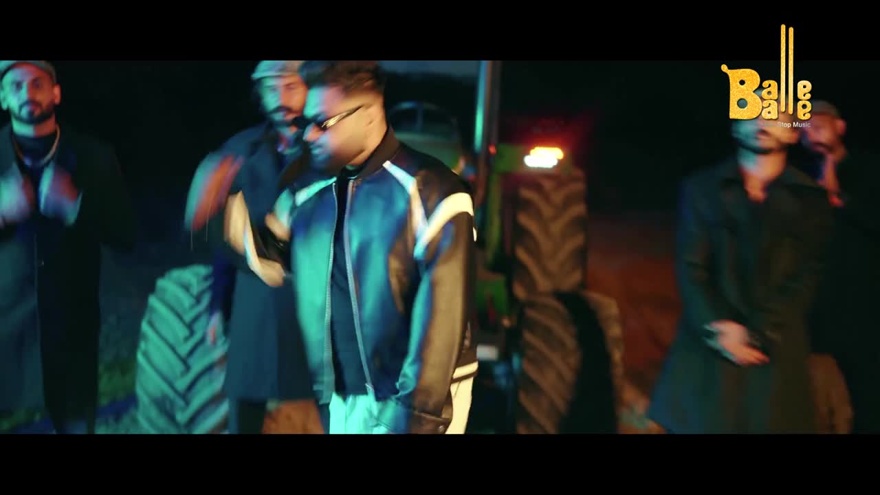 A man in a shiny black and white jacket moves with purpose, his sunglasses reflecting the dim lights. Behind him, a green tractor stands ready, and other men in traditional Indian attire are gathered. The "Balle Balle" logo, a vibrant yellow, sits prominently in the upper right corner.