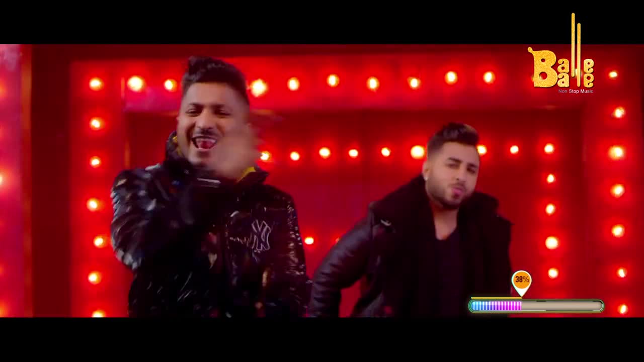 Two men stand on a stage lit by a wall of red lights. The man on the left, with a wide smile, exhales a puff of smoke. The man on the right, looking forward, has his hands clasped.