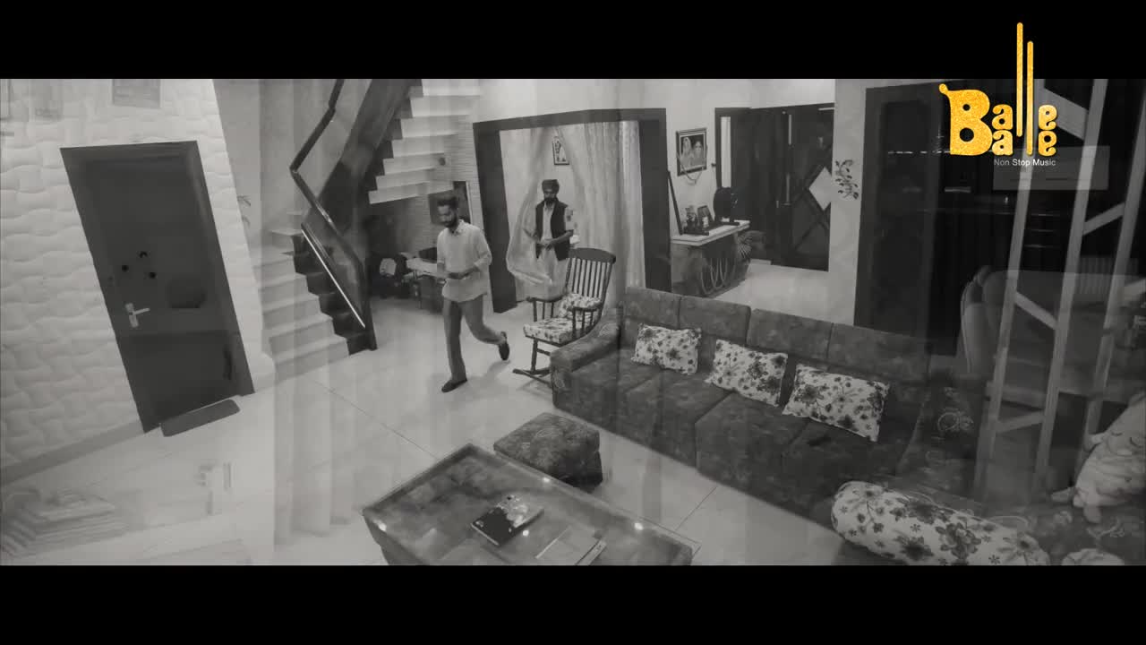 A man in a light shirt sprints past a staircase and a doorway. Another man, wearing a vest over a traditional kurta, stands near a rocking chair.