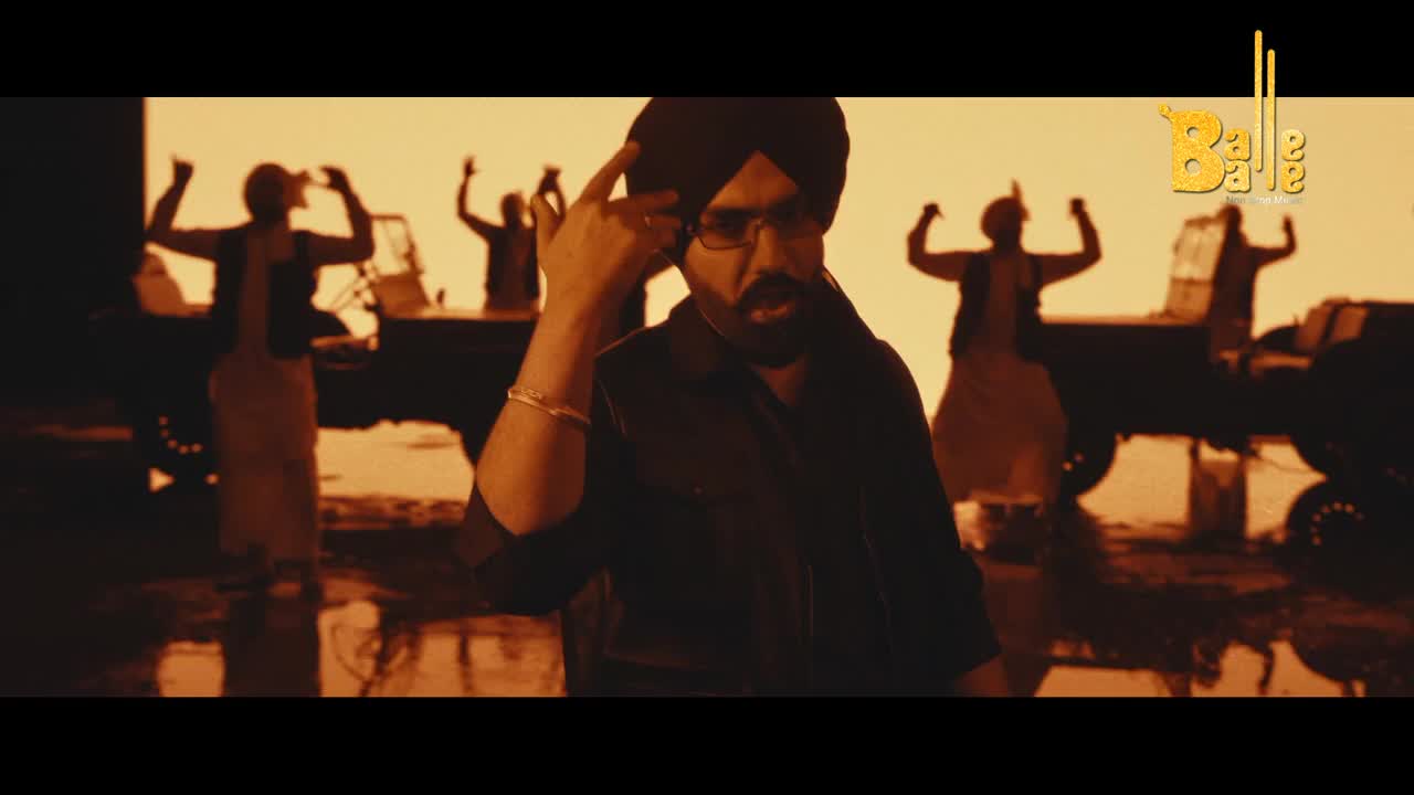 A man in a turban and glasses gestures with his hand to his temple. Behind him, figures dance with their arms raised in front of jeeps.