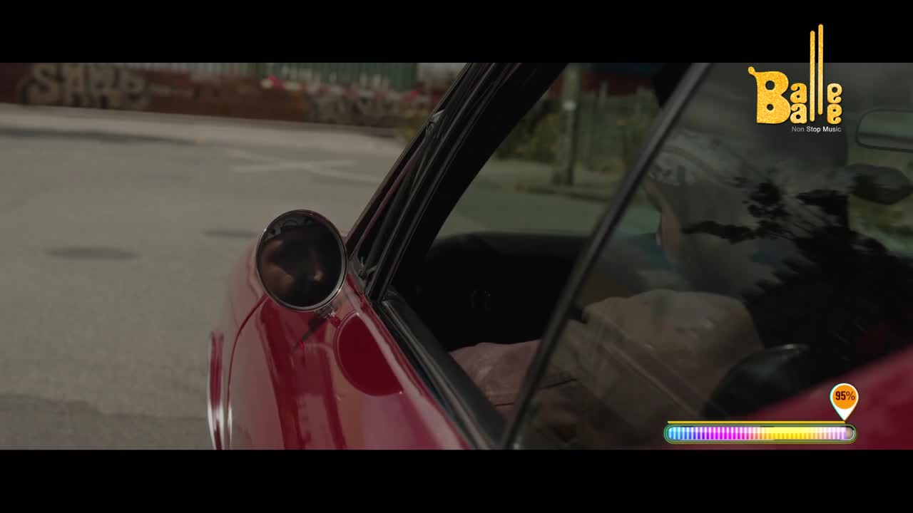 A red car is parked on a street, its door open. A person is visible inside, and the "Balle Balle" logo appears on the window.