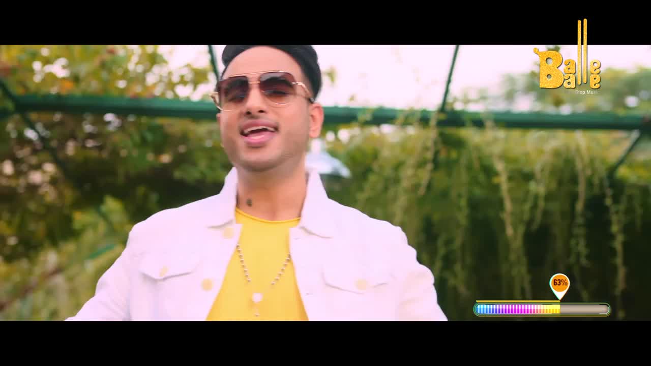 A man in a white jacket and yellow shirt sings with his mouth open, his sunglasses reflecting the light. The Balle Balle logo appears in the upper right corner.