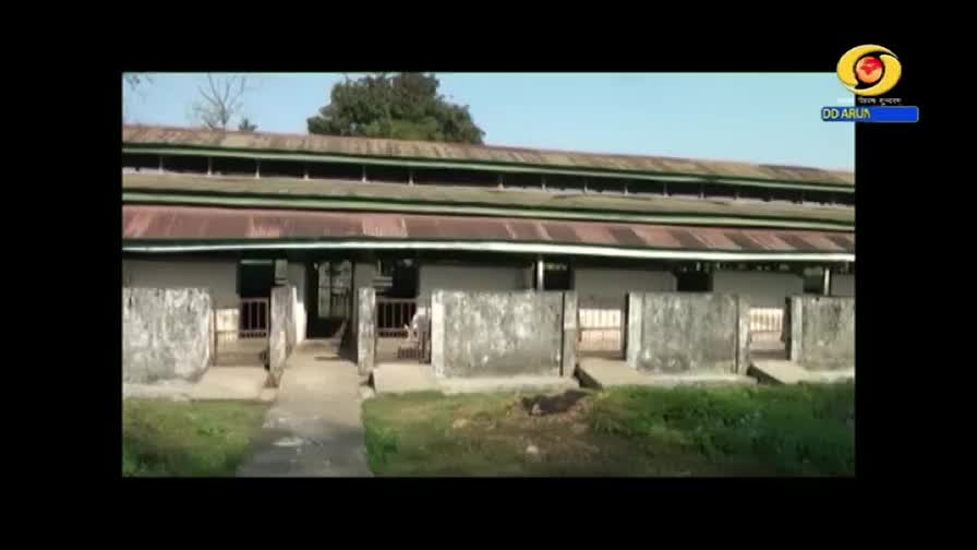 The camera focuses on a long, low building with a corrugated metal roof. A DD Arun Prabha logo sits in the corner, and the scene feels quiet and still.
