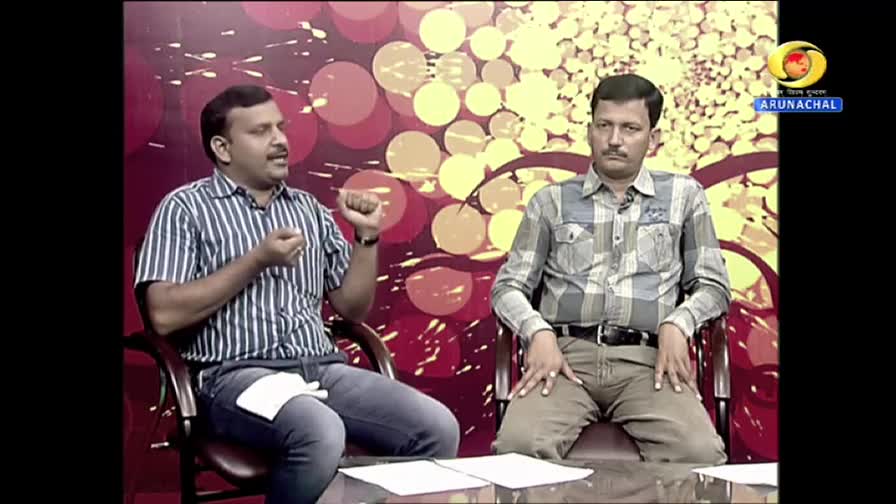 On the DD Arun Prabha set, a man in a striped shirt gestures emphatically, while the other, in a checkered shirt, sits still. A logo for Arunachal Pradesh is visible in the corner.
