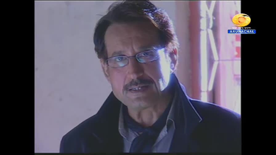 A man in glasses, with a mustache, is speaking on what appears to be a DD Arun Prabha broadcast. The logo for Arunachal is visible in the corner.
