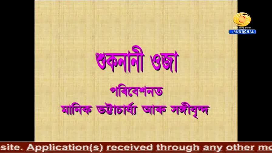 On the DD Arun Prabha screen, a title card displays text in Assamese, the words in vibrant purple. The logo for Arunachal Pradesh is in the top right corner.
On the DD Arun Prabha screen, a title card displays text in Assamese, the words in vibrant purple. The logo for Arunachal Pradesh is in the top right corner.