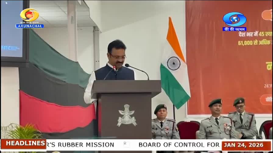 A man stands at a podium, speaking into a microphone. He's flanked by the Indian flag and two uniformed individuals. The DD Arun Prabha logo is visible in the corner. A man stands at a podium, speaking into a microphone. He's flanked by the Indian flag and two uniformed individuals. The DD Arun Prabha logo is visible in the corner.