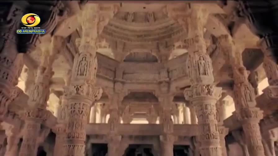 The camera pans slowly through a vast, ornate temple hall in India, revealing intricately carved marble pillars.  DD Arun Prabha's logo appears briefly in the upper left corner.