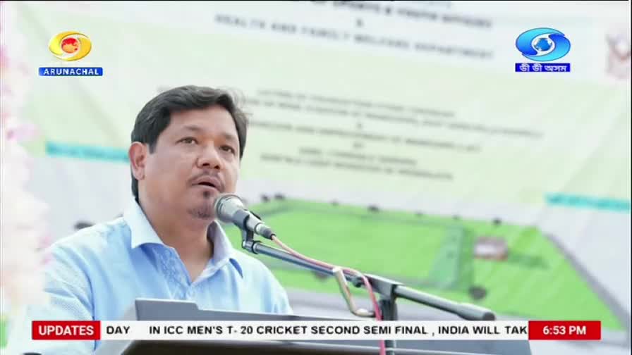 A man in a light blue shirt speaks into a microphone, his gaze directed forward. The DD Arun Prabha logo is visible in the upper left corner.