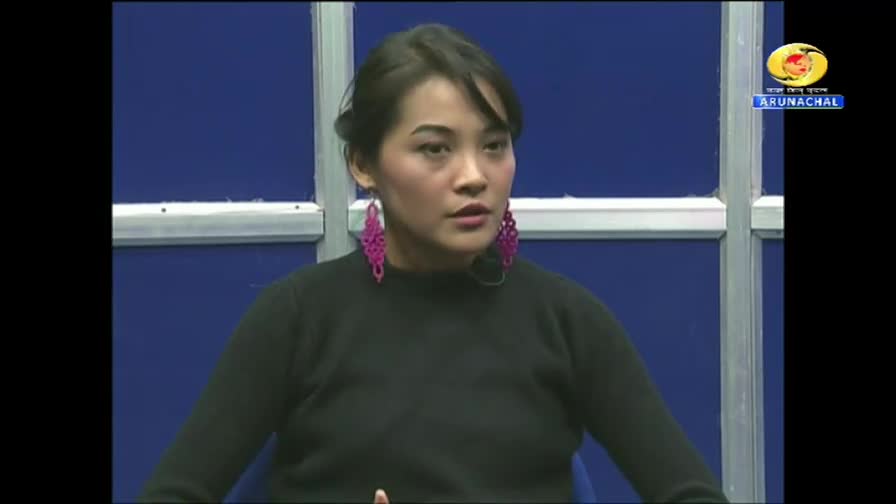 A woman with large, fuchsia earrings speaks into a microphone. A logo for DD Arun Prabha, a television channel from Arunachal Pradesh in India, appears in the upper right corner.