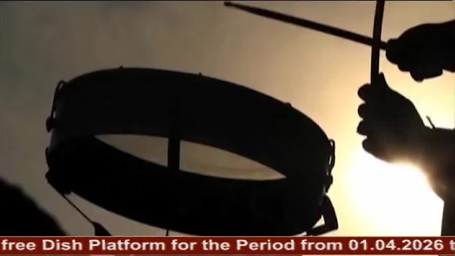 Drumsticks strike a large drum, silhouetted against a bright sky. This is part of a DD Arun Prabha broadcast.