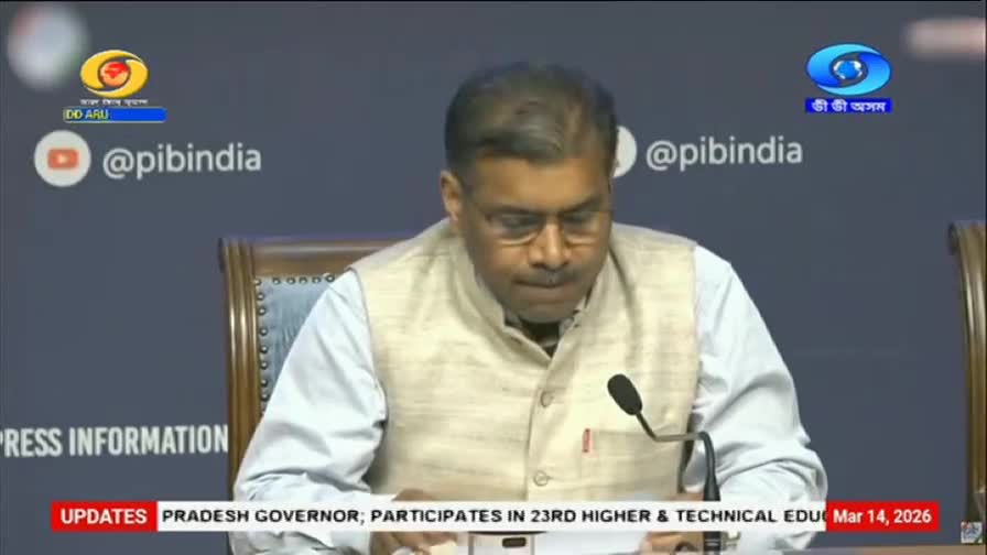 A man in a light-colored vest over a white shirt looks down at papers in front of him. The DD Arun Prabha logo is visible in the upper left corner, and the screen displays "UPDATES PRADESH GOVERNOR; PARTICIPATES IN 23RD HIGHER & TECHNICAL EDU Mar 14, 2026."