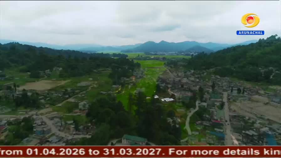 The camera pans over a valley in Arunachal Pradesh, revealing a sprawl of houses nestled among lush green hills. A bright DD Arun Prabha logo hovers in the corner of the sky. The camera pans over a valley in Arunachal Pradesh, revealing a sprawl of houses nestled among lush green hills. A bright DD Arun Prabha logo hovers in the corner of the sky.