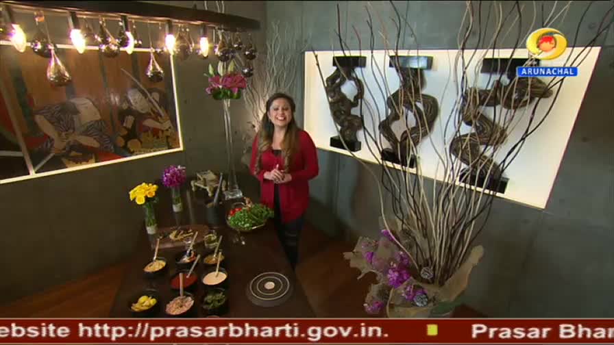 A woman in a red cardigan stands by a table laden with small bowls of food. The DD Arun Prabha logo is visible in the corner. A woman in a red cardigan stands by a table laden with small bowls of food. The DD Arun Prabha logo is visible in the corner.