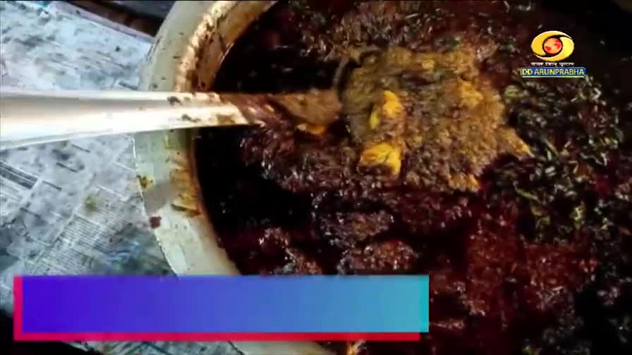 A ladle stirs a rich, dark curry, its surface glistening with oil. The aroma of spices fills the air, a familiar scent from a DD Arun Prabha broadcast.