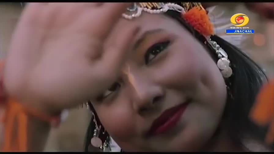 A young woman, adorned in traditional jewelry and makeup, smiles as her hand sweeps across her forehead. The DD Arun Prabha logo is visible in the corner, indicating a broadcast from India.